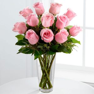 Florero de vidrio con rosas rosadas.